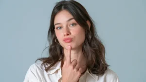 Mujer observando de cerca sus dientes y encías en el espejo con expresión de duda